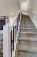 Carpeted staircase with white risers and handrails, complemented by black metal balusters - 