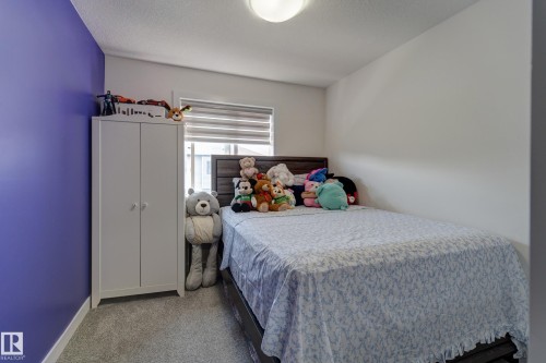 Bedroom featuring plush carpeting, a large window with horizontal blinds, and a built-in ceiling light fixture - #8 1703 16 Av Nw Nw, Edmonton, AB - Indoor Photo Showing Bedroom