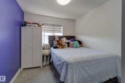Bedroom featuring plush carpeting, a large window with horizontal blinds, and a built-in ceiling light fixture - 