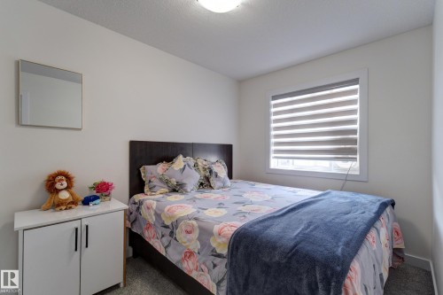 Bright room featuring a single window with blinds, light gray wall paint, and a dark wood-finish headboard - #8 1703 16 Av Nw Nw, Edmonton, AB - Indoor Photo Showing Bedroom