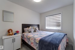 Bright room featuring a single window with blinds, light gray wall paint, and a dark wood-finish headboard - 