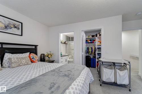 Bedroom featuring a dark wood headboard, light gray patterned bedding, and wall-to-wall carpeting - #8 1703 16 Av Nw Nw, Edmonton, AB - Indoor Photo Showing Bedroom