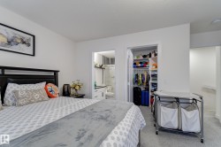 Bedroom featuring a dark wood headboard, light gray patterned bedding, and wall-to-wall carpeting - 