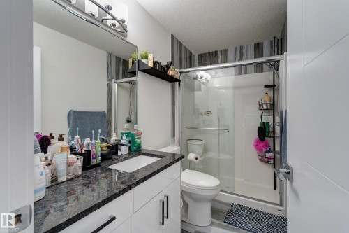 Modern bathroom featuring a single vanity with a granite countertop, white cabinetry, and a rectangular undermount sink - #8 1703 16 Av Nw Nw, Edmonton, AB - Indoor Photo Showing Bathroom