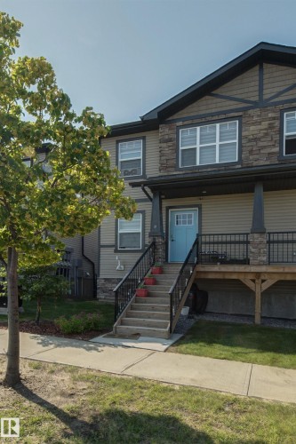 Multifaceted exterior featuring stone accents, horizontal siding, and a prominent front entrance with a bright blue door - #8 1703 16 Av Nw Nw, Edmonton, AB - Outdoor