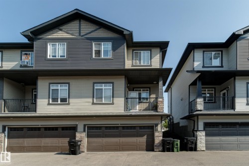 Multi-level townhouse exterior featuring horizontal siding in two-tone grey and beige, dark trim accents, multiple windows, and a prominent gable roofline - #8 1703 16 Av Nw Nw, Edmonton, AB - Outdoor With Facade