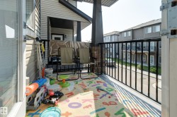 Spacious balcony featuring durable vinyl siding, a black metal railing, and a stone-clad column base - 