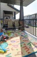 Covered front porch featuring durable vinyl siding, a stone-accented pillar, and a black metal railing - 
