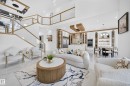 Open-concept living space featuring high ceilings and a grand staircase with glass railings and wood-finish accents - 112 Ross Close, Leduc, AB  - Indoor Photo Showing Living Room 