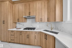 Kitchen featuring wood-finish cabinetry, white marble-look countertops, and a gas cooktop with a stainless steel range hood - 