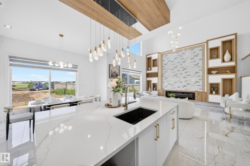 Open-concept interior featuring high ceilings and a built-in entertainment center with an electric fireplace - 112 Ross Close, Leduc, AB - Indoor Photo Showing Kitchen