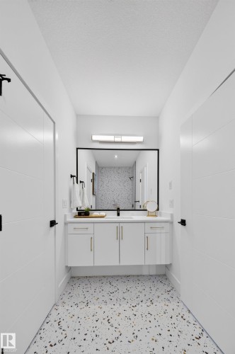 Bathroom featuring a floating double vanity with gold hardware, a large framed mirror, and a linear vanity light - 112 Ross Close, Leduc, AB - Indoor Photo Showing Other Room