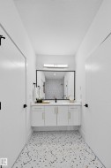 Bathroom featuring a floating double vanity with gold hardware, a large framed mirror, and a linear vanity light - 