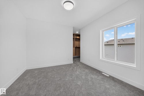 Spacious room featuring gray carpeting, white baseboards, and a large window providing ample natural light - 112 Ross Close, Leduc, AB - Indoor Photo Showing Other Room