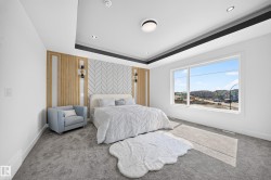 Expansive bedroom featuring a tray ceiling with recessed lighting, a large window, and patterned accent wall - 