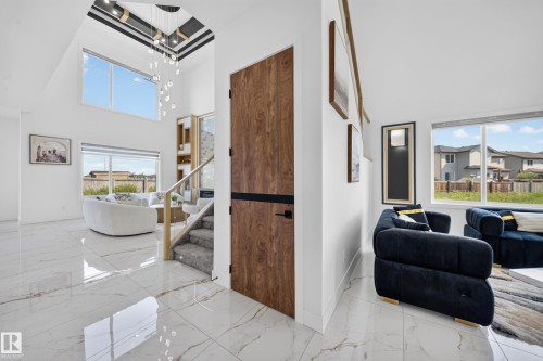 Vaulted ceiling with an intricate chandelier, large format tile flooring, and a contemporary staircase with carpeted treads - 112 Ross Close, Leduc, AB - Indoor Photo Showing Other Room
