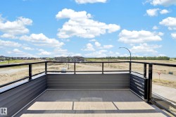 Balcony featuring composite decking, dark gray horizontal siding, and a black metal railing with glass panels - 