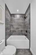Shower-tub combination featuring large format grey tile surround and matte black fixtures - 