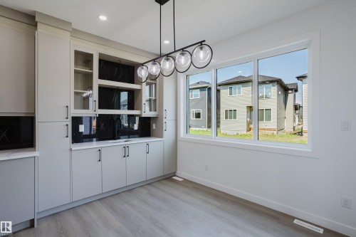 Built-in wet bar featuring light grey cabinetry, black marble-look backsplash, an undermount sink, and a quartz countertop - 8728 182 Avenue Nw, Edmonton, AB - Indoor