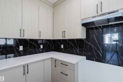 Kitchen featuring light wood-finish upper cabinetry, light gray base cabinetry, and matte black hardware - 8728 182 Avenue Nw, Edmonton, AB - Indoor Photo Showing Kitchen
