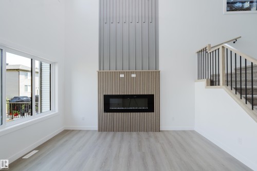 Modern living area featuring a floor-to-ceiling fireplace with wood slat detailing and an electric insert - 8728 182 Avenue Nw, Edmonton, AB - Indoor Photo Showing Living Room With Fireplace