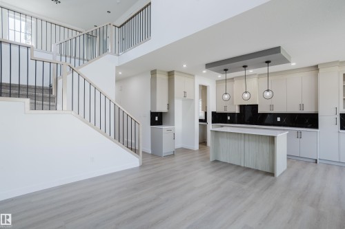 Open-concept living area featuring a modern kitchen and an elegant staircase - 8728 182 Avenue Nw, Edmonton, AB - Indoor Photo Showing Kitchen