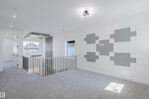 Spacious upper level featuring light gray carpet flooring, a decorative accent wall with geometric white paneling, and recessed ceiling lighting - 8728 182 Avenue Nw, Edmonton, AB - Indoor Photo Showing Other Room