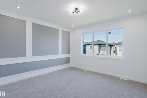 Bright room with grey accent wall featuring decorative panel molding and white trim - 8728 182 Avenue Nw, Edmonton, AB - Indoor Photo Showing Other Room
