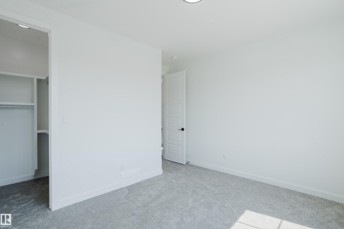 Neutral-toned room featuring light gray carpeting, white walls, and a built-in closet with shelving and hanging space - 8728 182 Avenue Nw, Edmonton, AB - Indoor Photo Showing Other Room