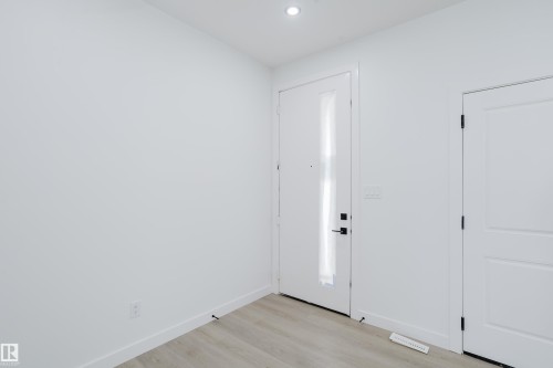 Entryway featuring a contemporary white door with vertical glass insert, light wood-finish flooring, recessed ceiling lighting, and crisp white walls - 8728 182 Avenue Nw, Edmonton, AB - Indoor Photo Showing Other Room