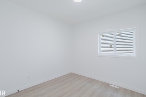 Neutral-toned wood-finish flooring complements white walls, a white trim window, and a flush-mounted ceiling light - 8728 182 Avenue Nw, Edmonton, AB - Indoor Photo Showing Other Room