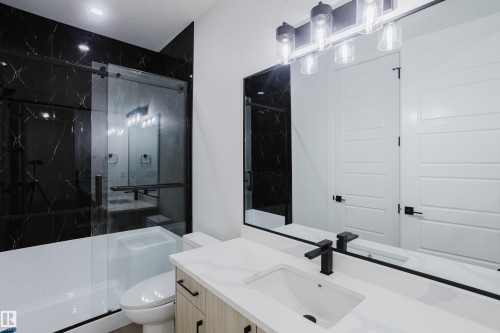 Bathroom featuring a wood-finish vanity with a white countertop, undermount sink, and matte black faucet - 8728 182 Avenue Nw, Edmonton, AB - Indoor Photo Showing Bathroom
