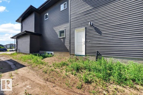Contemporary dark gray horizontal siding exterior with contrasting white entry door - 6001 19 Street, Nisku, AB - Outdoor