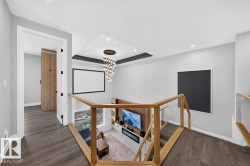 Contemporary upper-level landing featuring wood-finish flooring, recessed lighting, and a unique chandelier - 