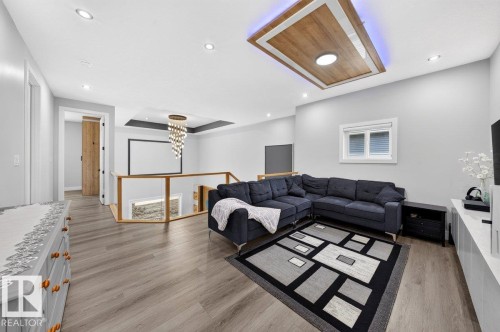 Spacious upper-level living area featuring wood-finish flooring, recessed lighting, and a modern ceiling detail with integrated lighting - 6001 19 Street, Nisku, AB - Indoor Photo Showing Living Room