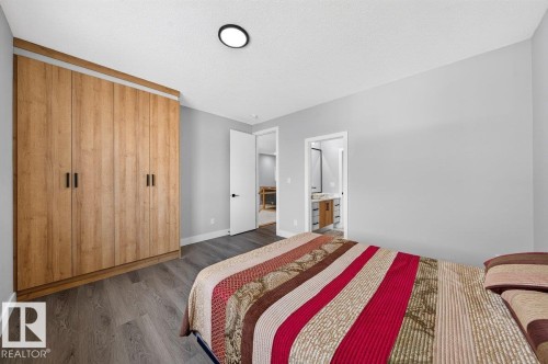 Built-in wood-finish wardrobe with contemporary black handles - 6001 19 Street, Nisku, AB - Indoor Photo Showing Bedroom