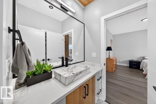 Modern bathroom featuring a rectangular vessel sink with a marble-effect finish, a matte black faucet, and a large wall-mounted mirror - 6001 19 Street, Nisku, AB - Indoor Photo Showing Bathroom
