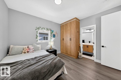 Neutral gray walls complemented by wood-finish flooring - 6001 19 Street, Nisku, AB - Indoor Photo Showing Bedroom