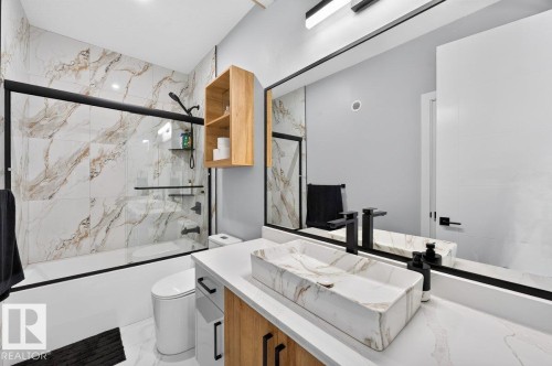 Contemporary bathroom featuring a rectangular vessel sink with a marbling pattern, a black wall-mounted faucet, and a large vanity mirror - 6001 19 Street, Nisku, AB - Indoor