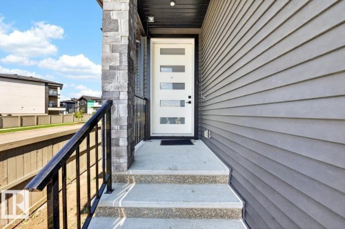 Modern entry door with five frosted glass panels, complemented by a stone facade accent and horizontal grey siding - 6001 19 Street, Nisku, AB - Outdoor With Exterior