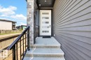 Modern entry door with five frosted glass panels, complemented by a stone facade accent and horizontal grey siding - 6001 19 Street, Nisku, AB  - Outdoor With Exterior 
