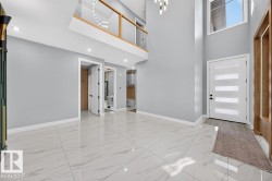 Two-story entryway featuring high ceilings, large format tile flooring, and a contemporary light fixture - 