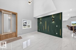 Soaring ceilings with an elegant decorative accent wall, featuring integrated sconce lighting and vertical gold-tone detailing - 