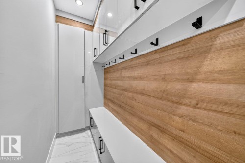 Built-in entryway organization system featuring wood-finish paneling, white cabinetry, and matte black hardware - 6001 19 Street, Nisku, AB - Indoor Photo Showing Other Room