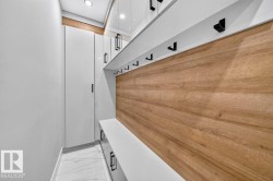 Built-in entryway organization system featuring wood-finish paneling, white cabinetry, and matte black hardware - 