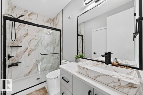 Modern bathroom featuring a glass-enclosed shower with black trim, a rectangular vessel sink with a dark faucet, and a large wall-mounted mirror - 6001 19 Street, Nisku, AB - Indoor Photo Showing Bathroom