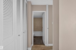 Hallway with louvered bi-fold doors, neutral wall paint, and white baseboards - 