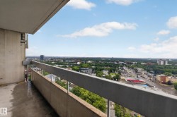 Expansive balcony with concrete flooring, a solid railing, and widespread urban and treeline scenery - 