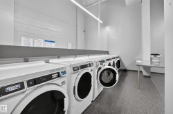 Laundry facility featuring multiple front-loading washing machines, durable flooring, and a folding counter - 