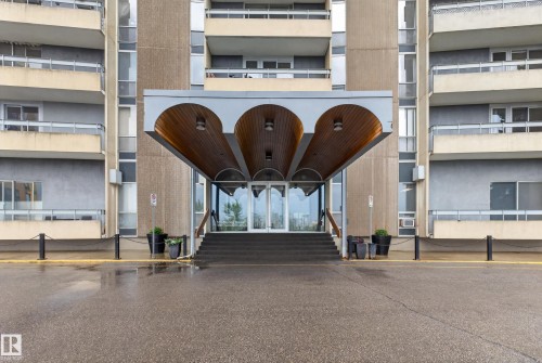 Building entrance featuring a contemporary arched porte-cochère with wood-finish soffits and recessed lighting - #1804 10883 Saskatchewan Dr Nw, Edmonton, AB - Outdoor With Balcony